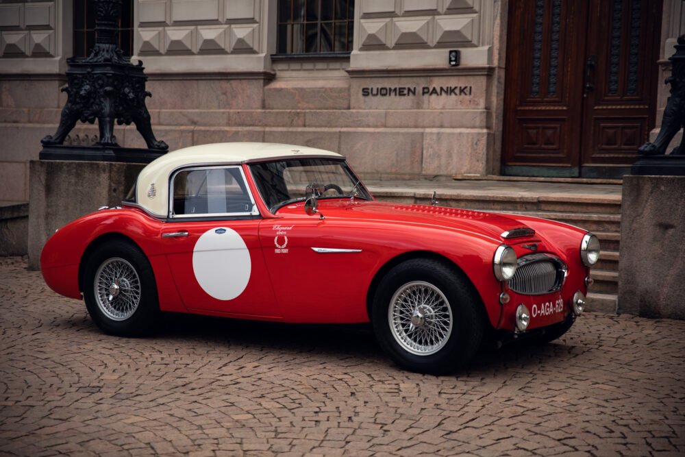 Vintage red sports car parked outside historic building.