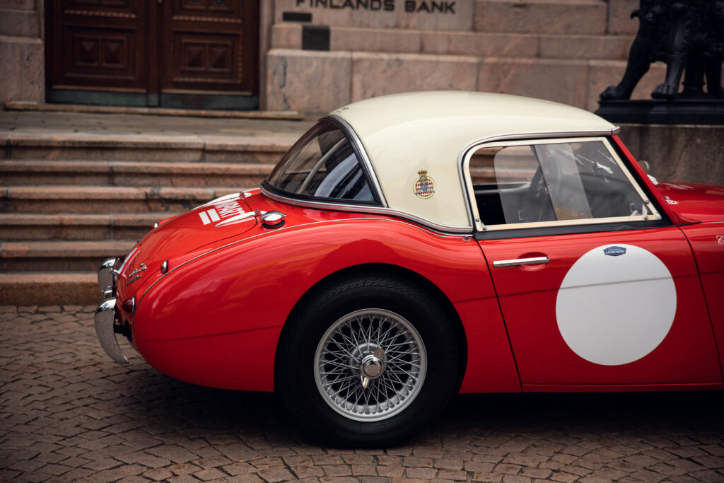 Vintage red sports car parked outside ornate building.