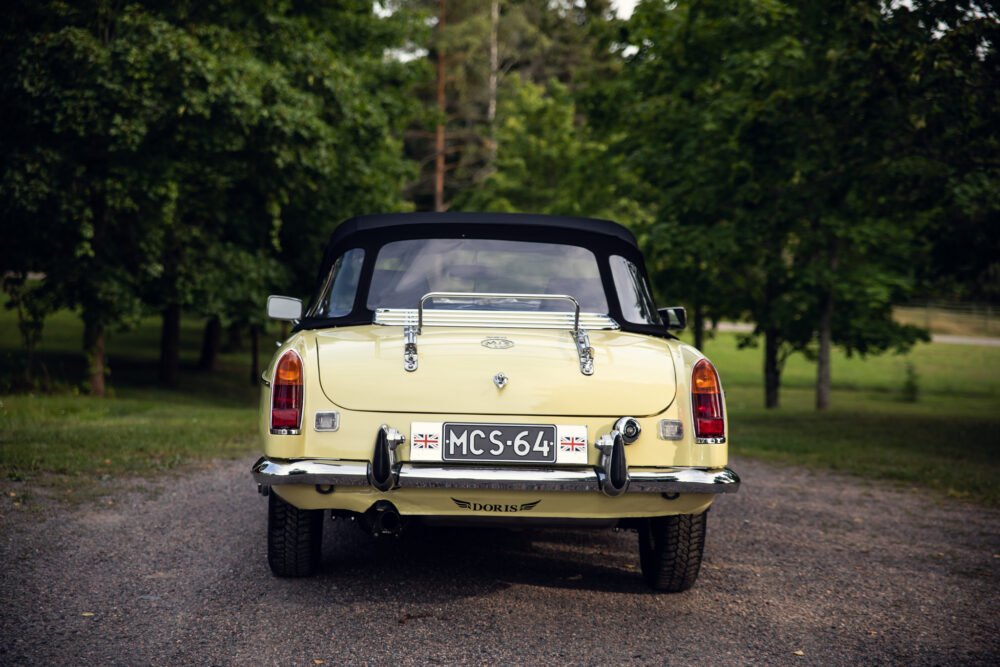 Yellow vintage convertible car in lush green park.