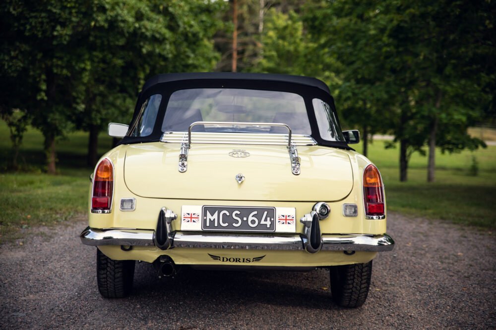 Vintage yellow convertible car, British flag on license plate.