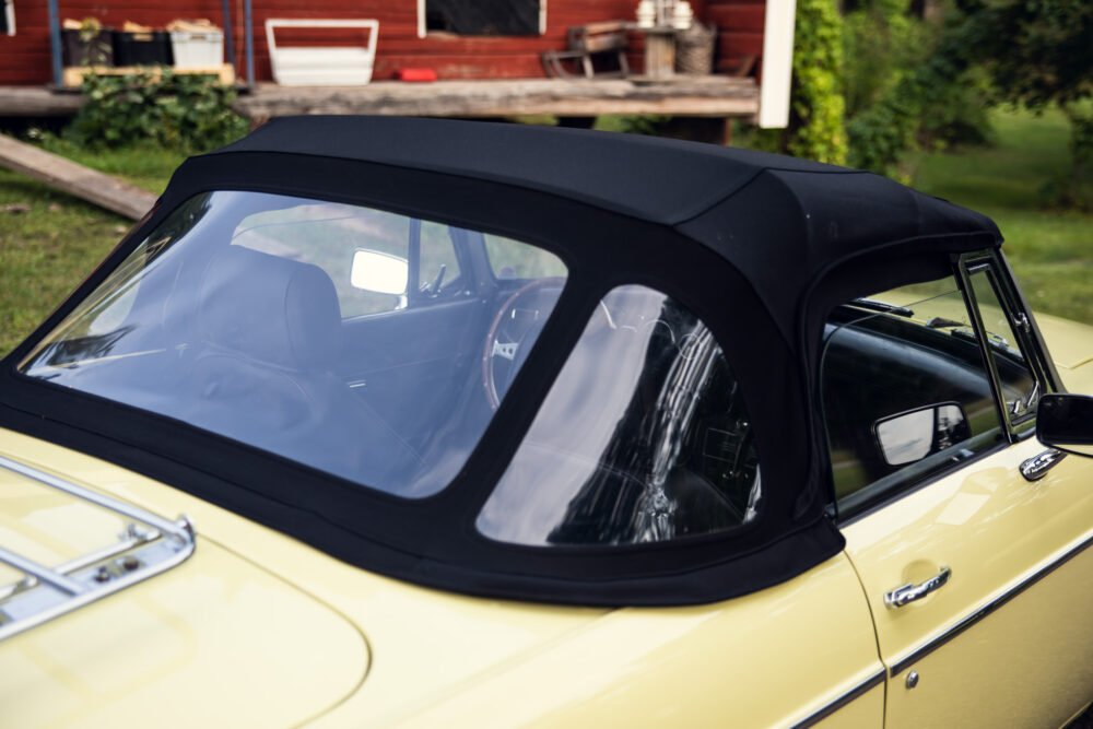 Yellow vintage convertible car with black soft top.