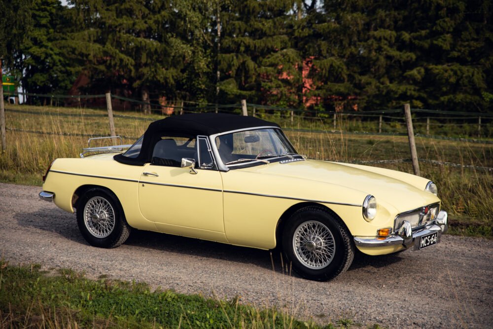 Vintage yellow convertible car parked in natural setting.