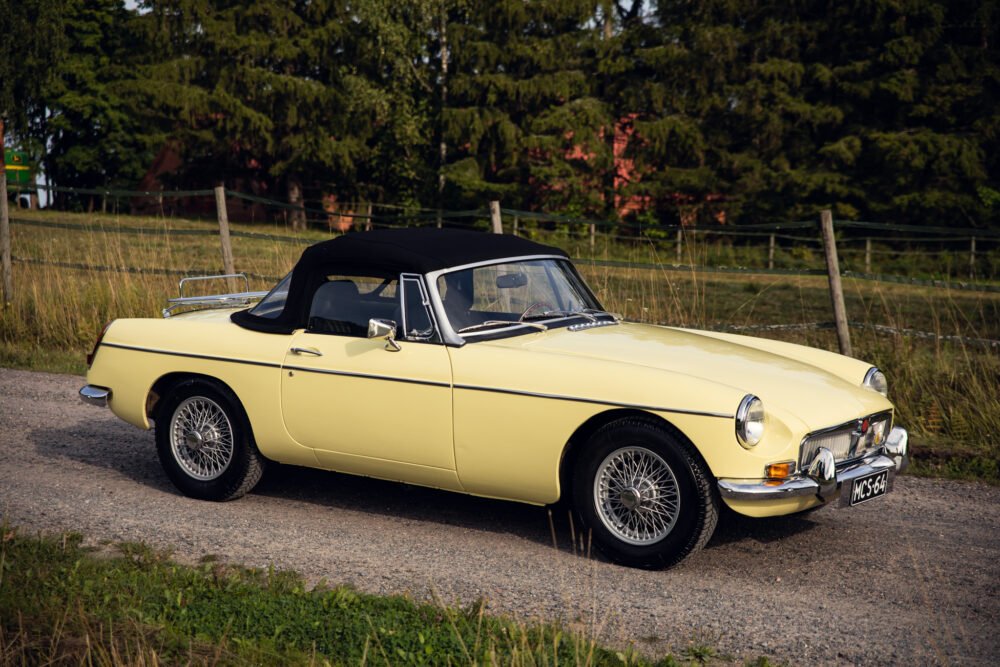 Vintage yellow convertible car on rural road.