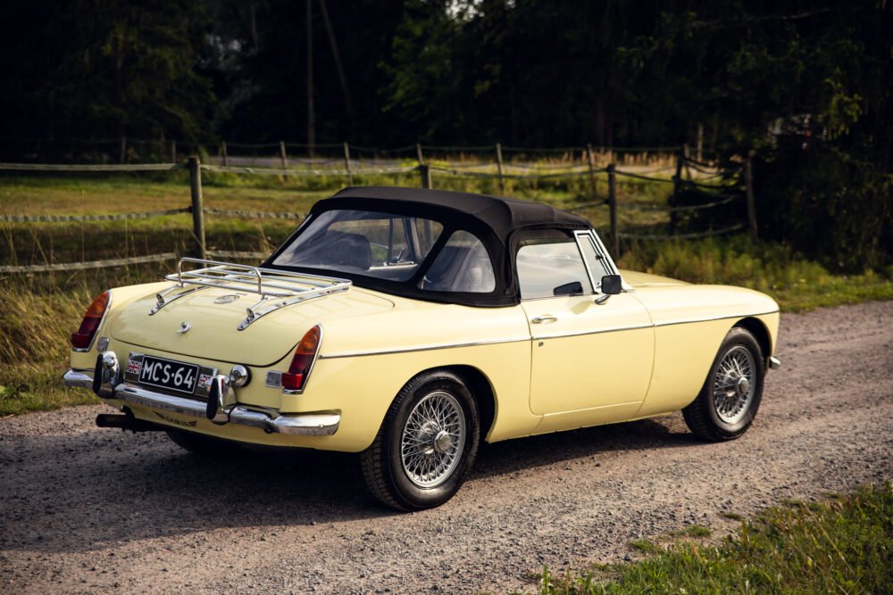 Vintage yellow convertible car parked in countryside.