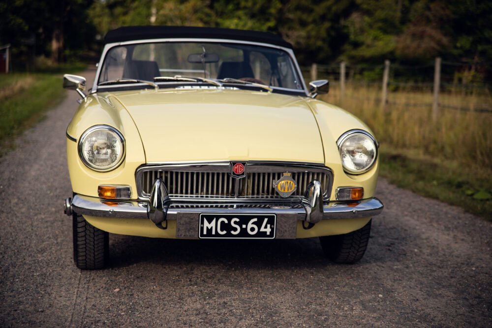 Vintage yellow MG convertible car on rural road.