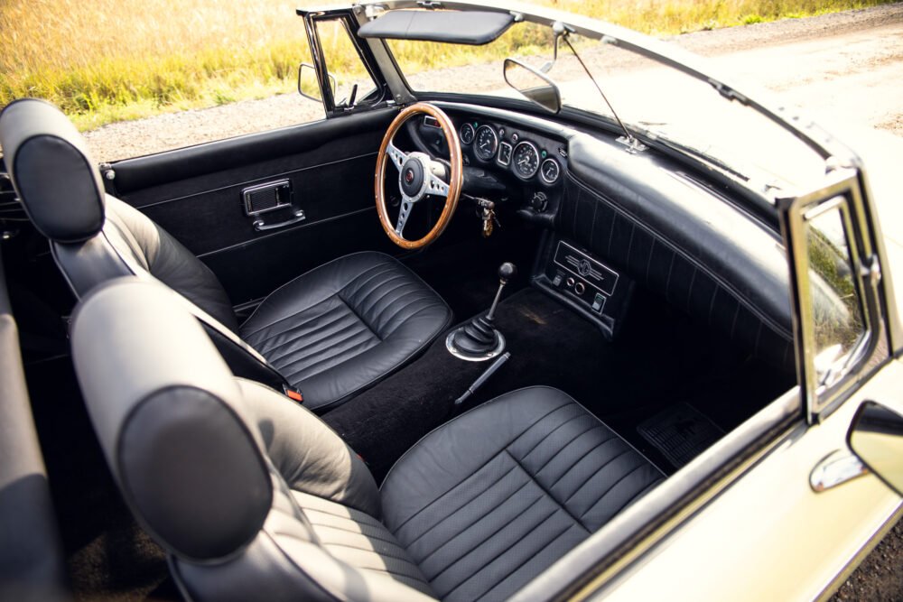 Classic car interior with leather seats and wooden steering wheel.