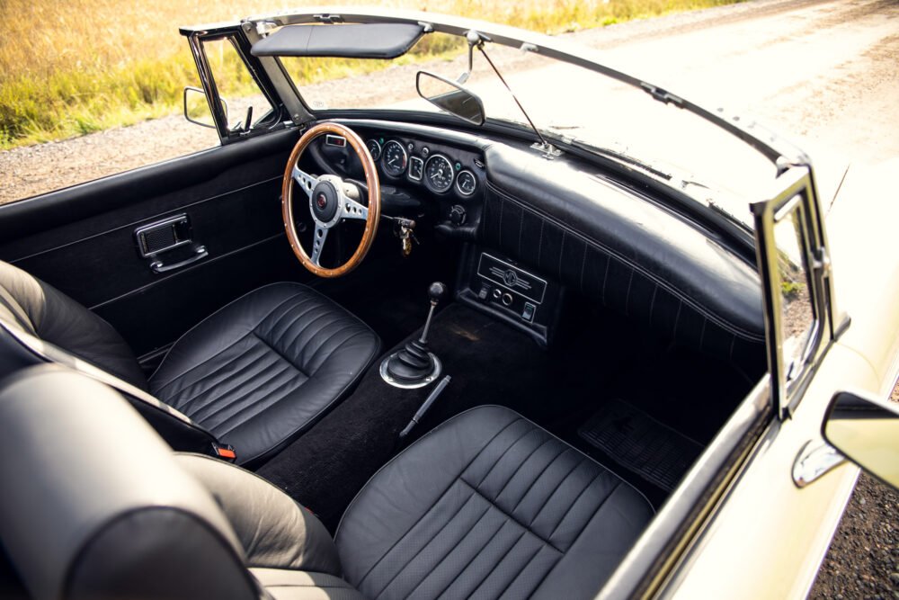 Vintage convertible car interior with wooden steering wheel.