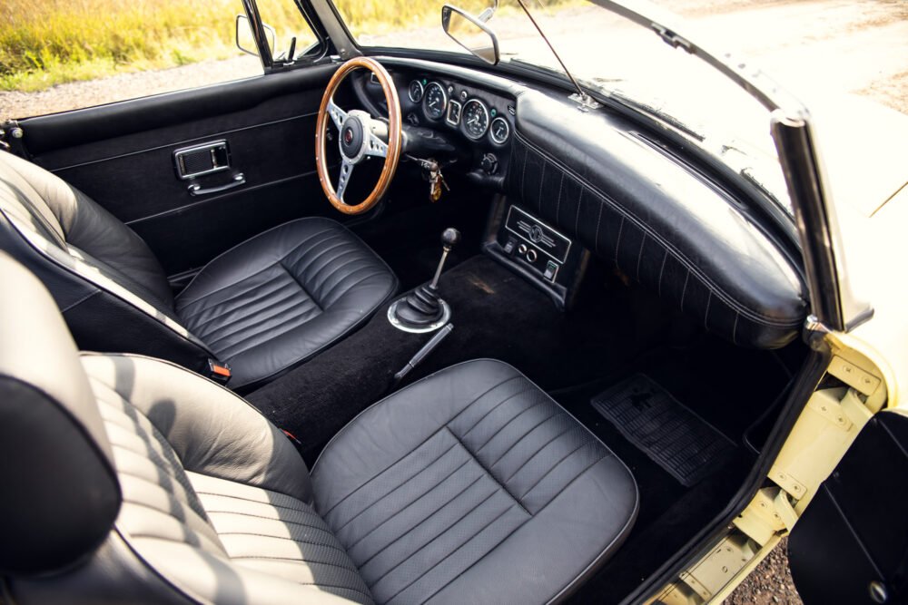 Vintage car interior with wooden steering wheel and leather seats.