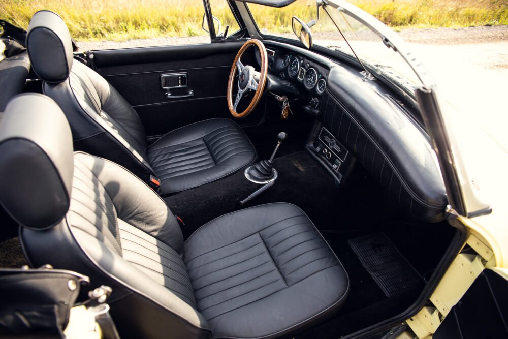 Vintage convertible car interior with wooden steering wheel.