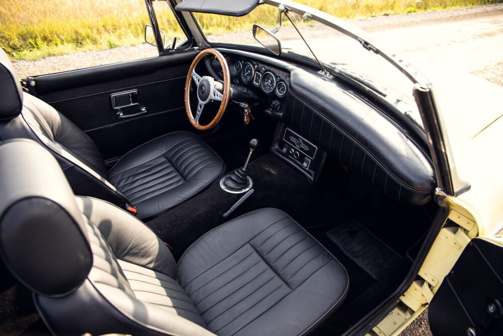 Vintage car interior with leather seats and wooden steering wheel.