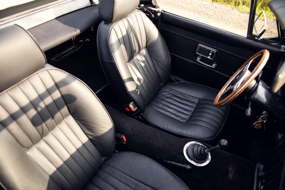 Vintage car interior with leather seats and wooden steering wheel.