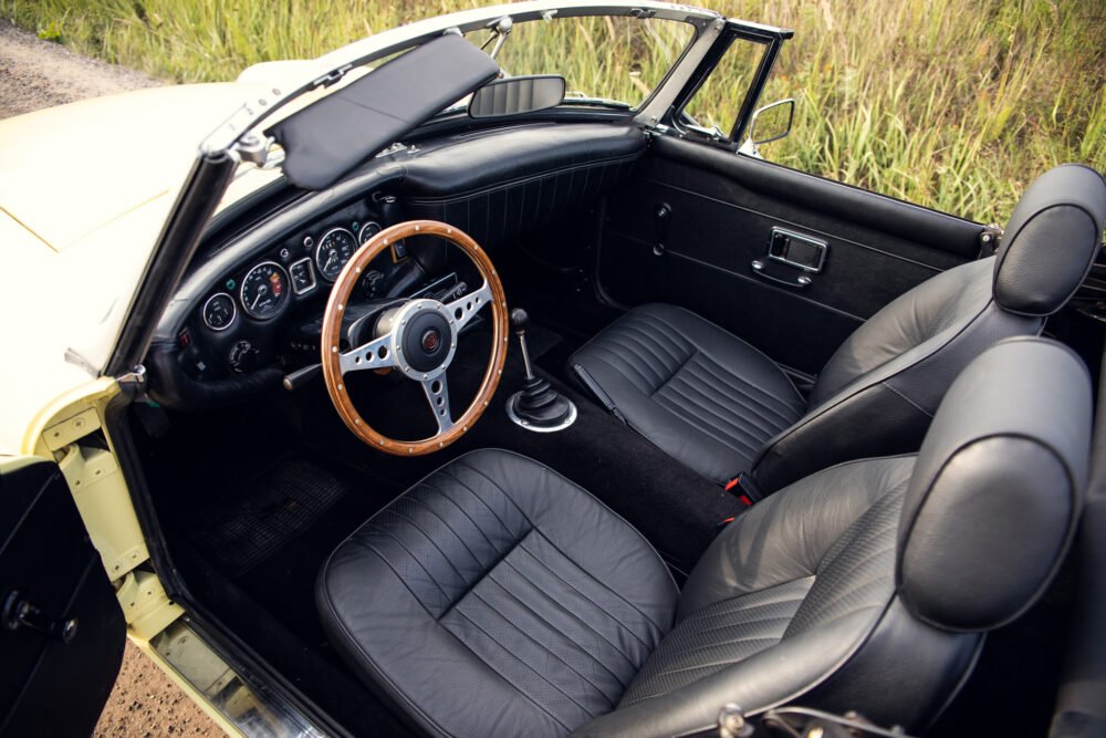 Vintage convertible car interior with wooden steering wheel.