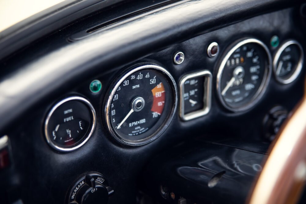 Vintage car dashboard with gauges and wooden detail.