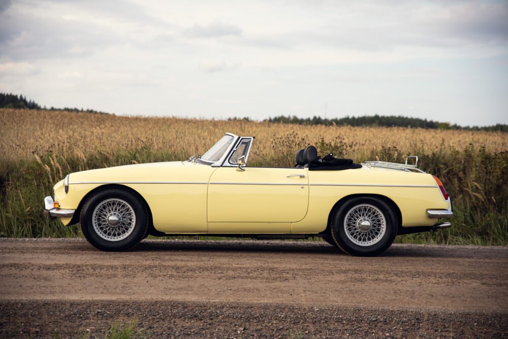 Yellow vintage convertible car beside a field.