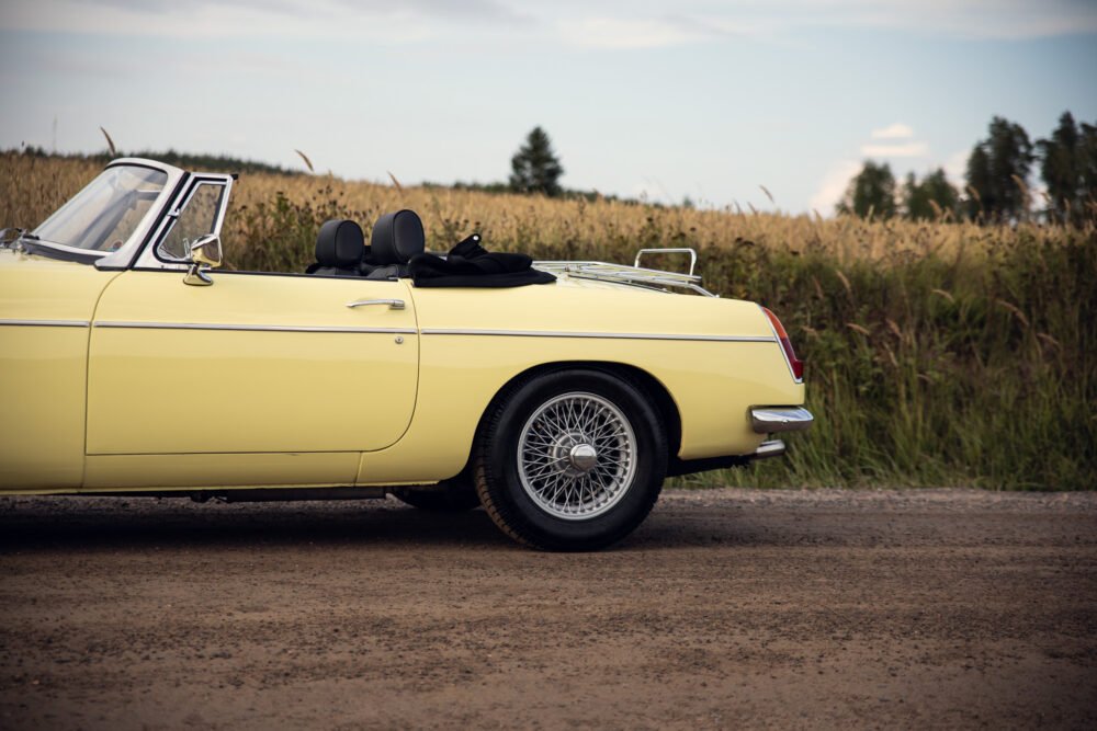 Yellow vintage convertible car on rural road.