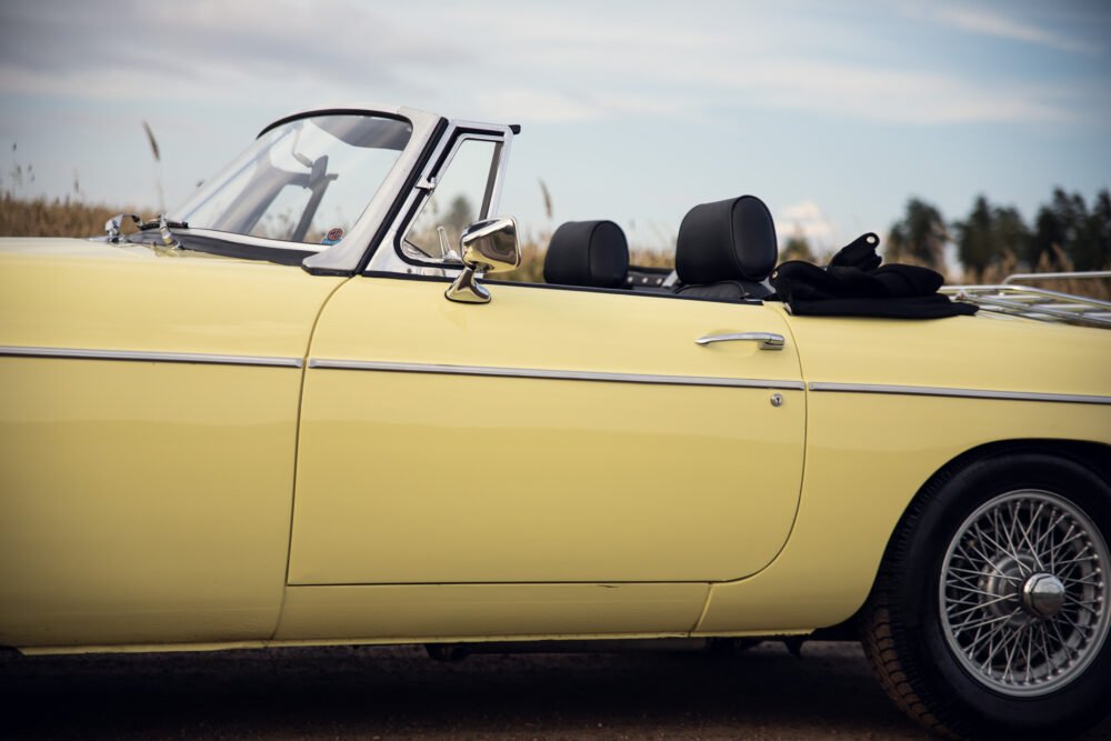 Yellow vintage convertible car parked outdoors.