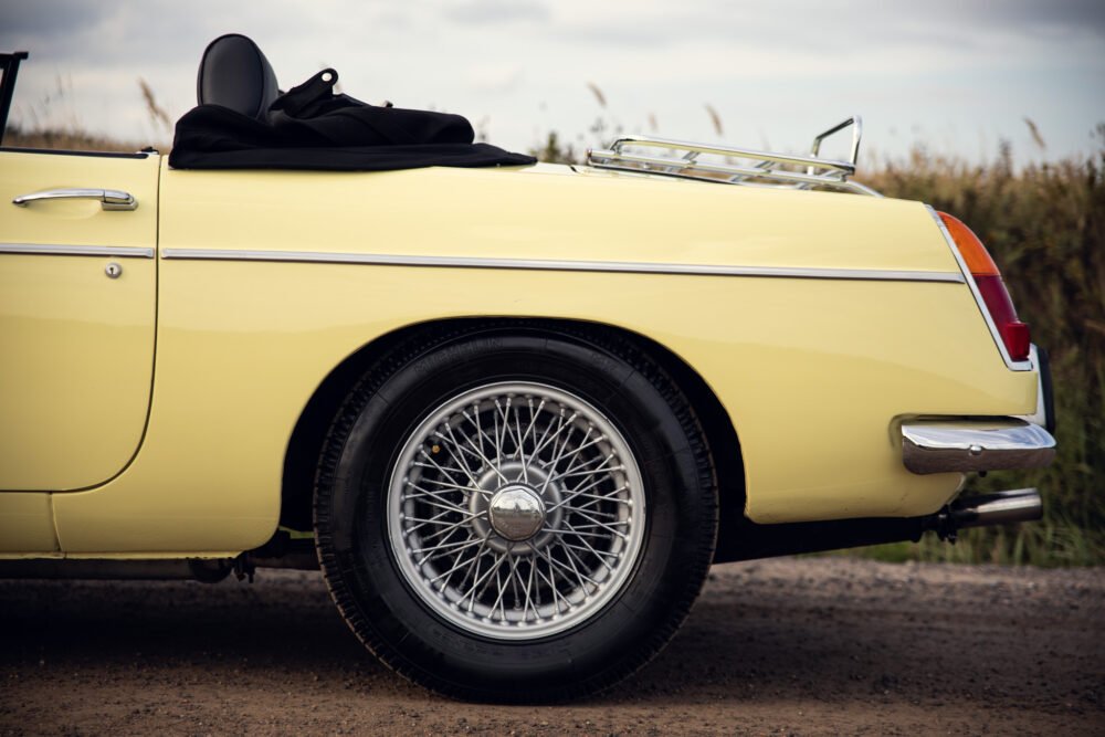 Yellow vintage convertible car with wire wheels.