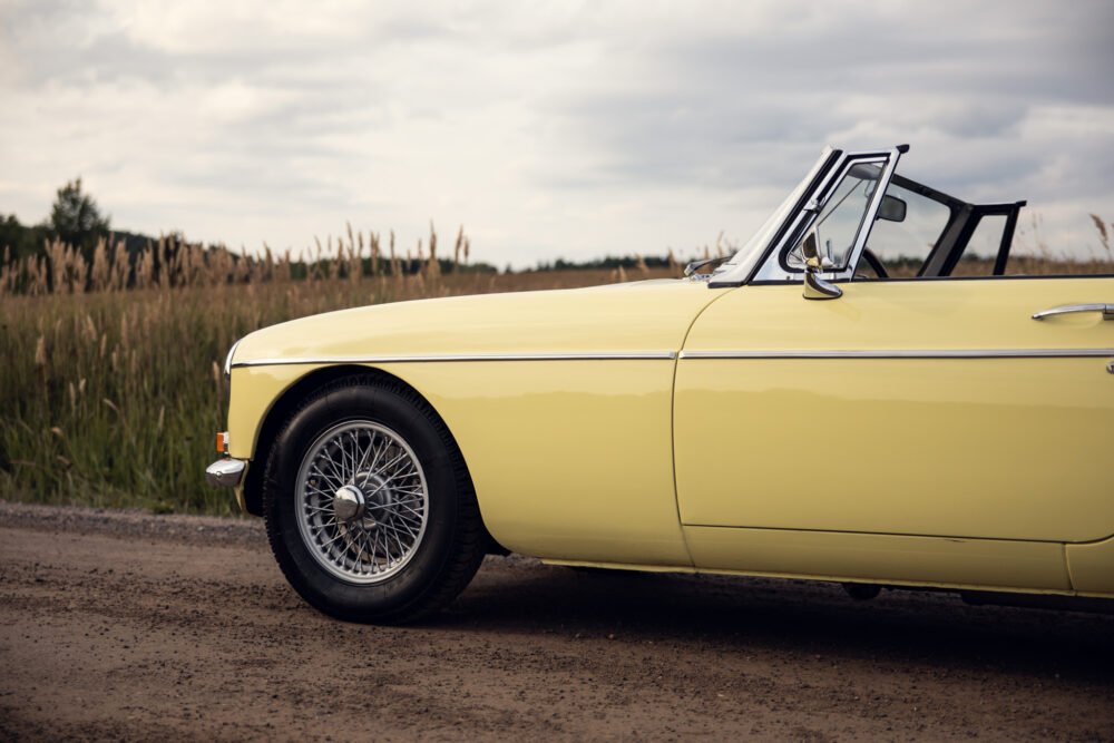 Vintage yellow convertible car on rural road.