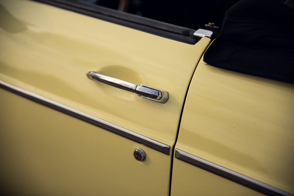 Close-up of yellow vintage car door and handle.