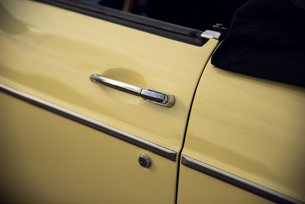 Close-up of yellow vintage car door and handle.