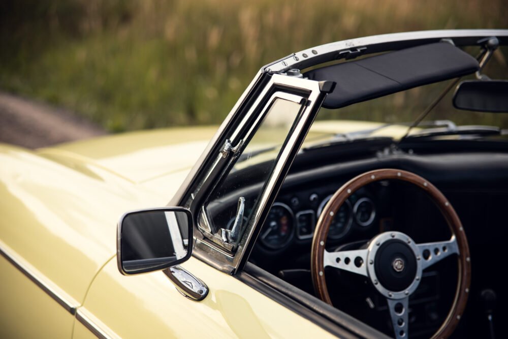 Vintage yellow convertible car with open door and mirror.