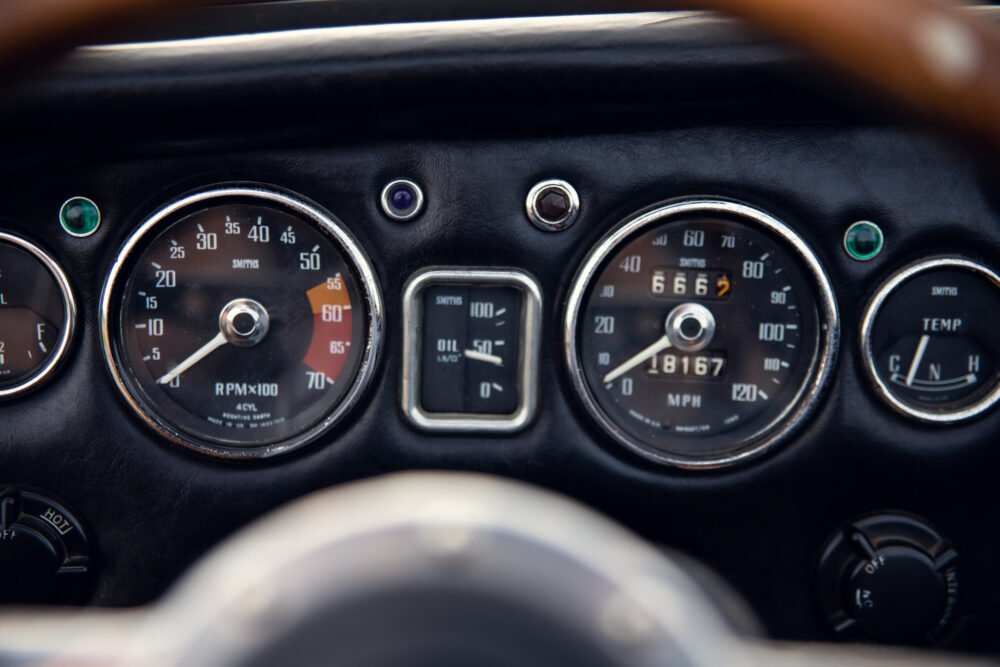 Vintage car dashboard with gauges and steering wheel visible.