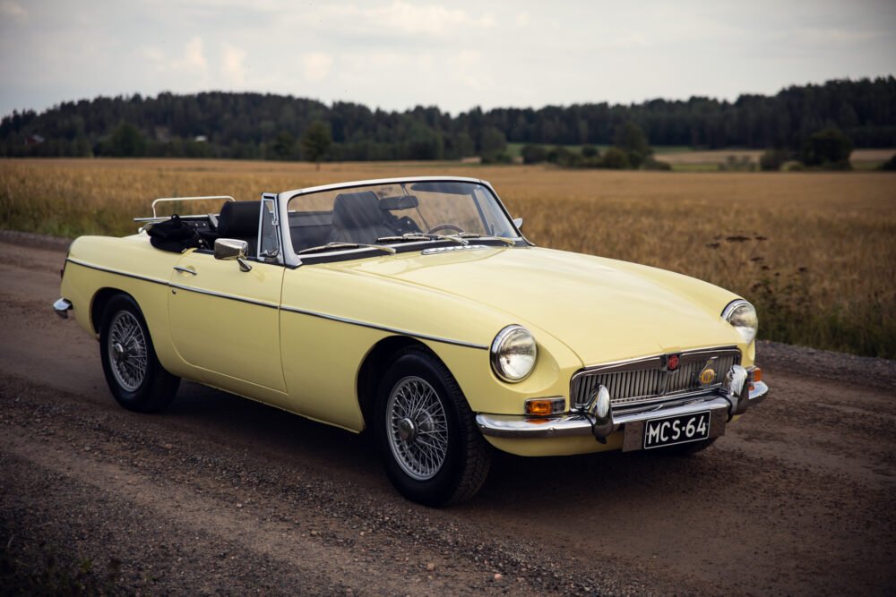 Vintage yellow convertible car on rural road.