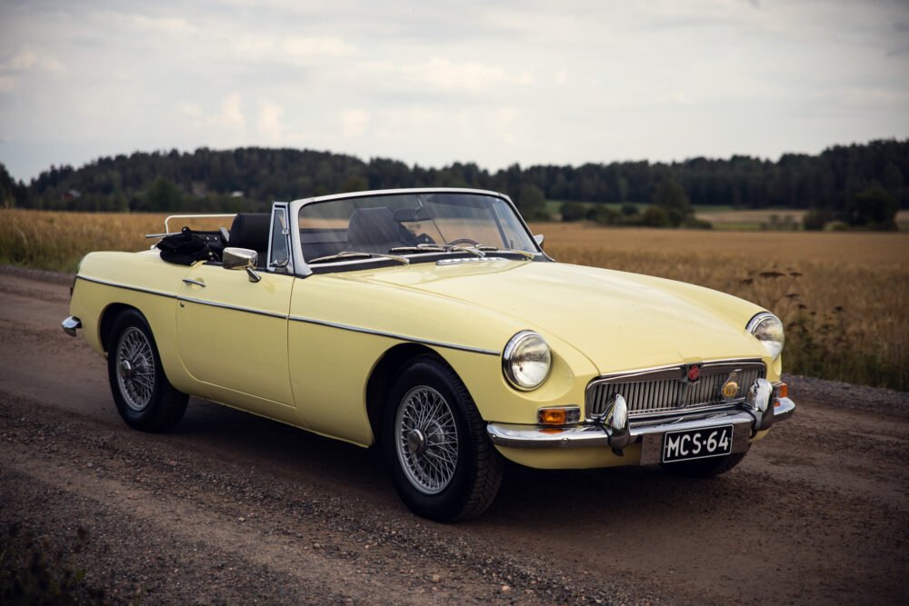 Yellow vintage convertible car on rural road.