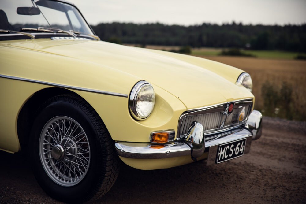 Vintage yellow MG convertible on rural road.