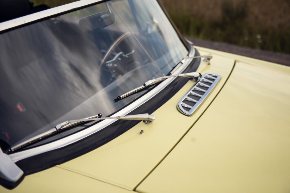 Close-up of vintage yellow car's windshield and hood.