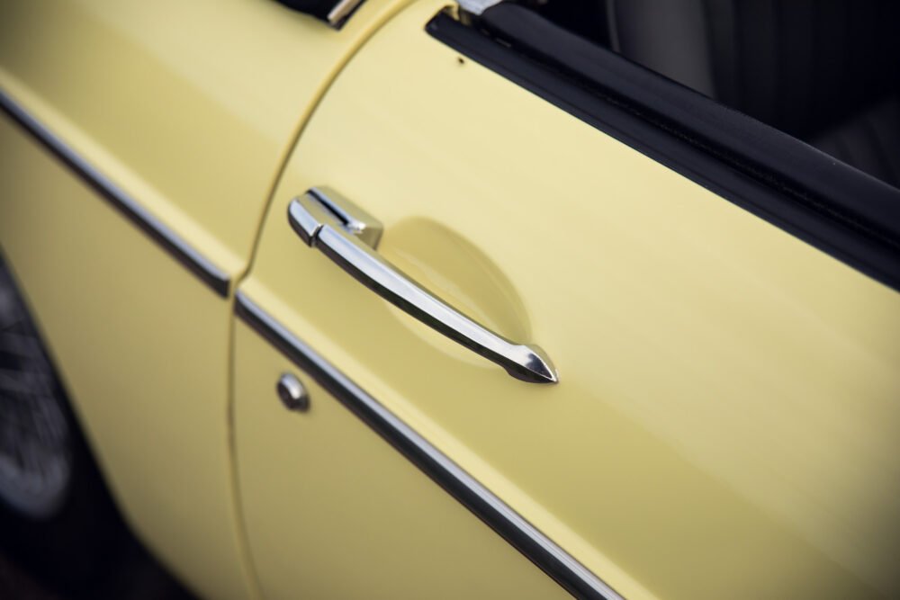 Yellow vintage car door and chrome handle.