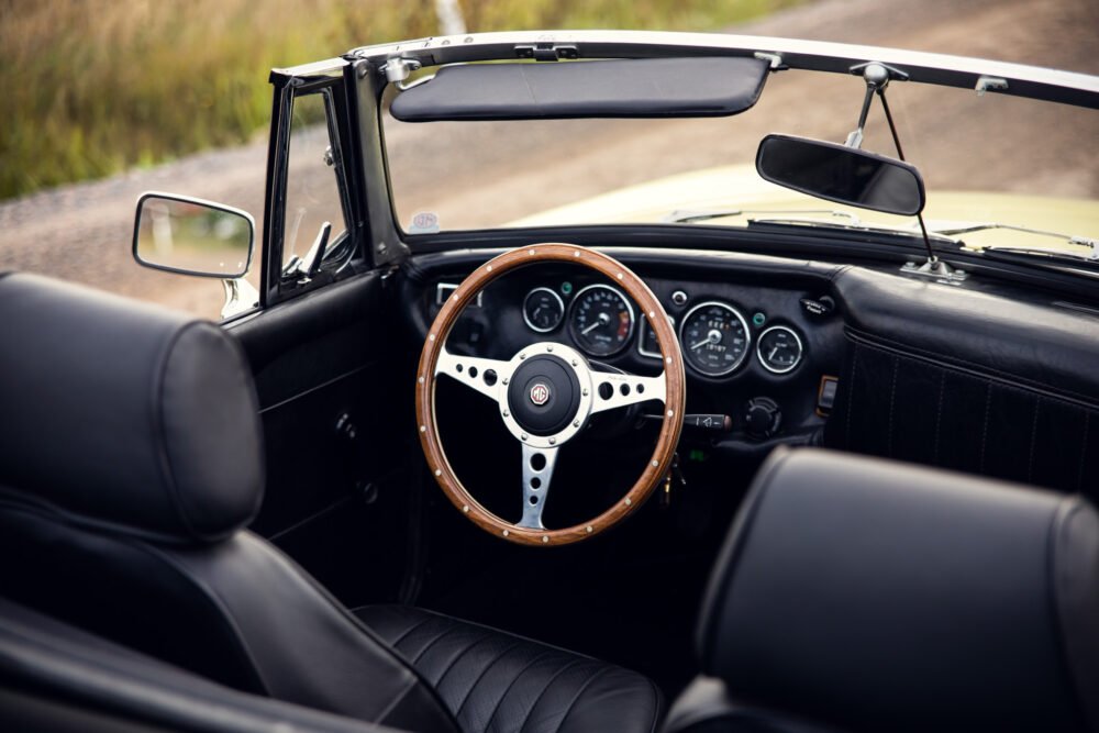 Vintage convertible car interior with wooden steering wheel.