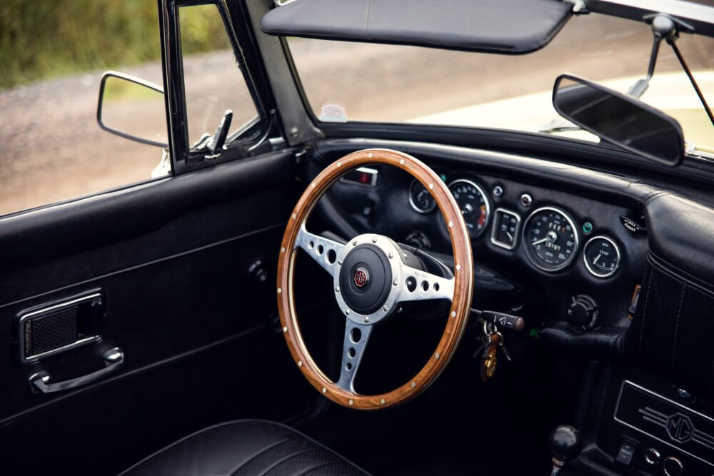 Vintage MG car's wooden steering wheel and dashboard.