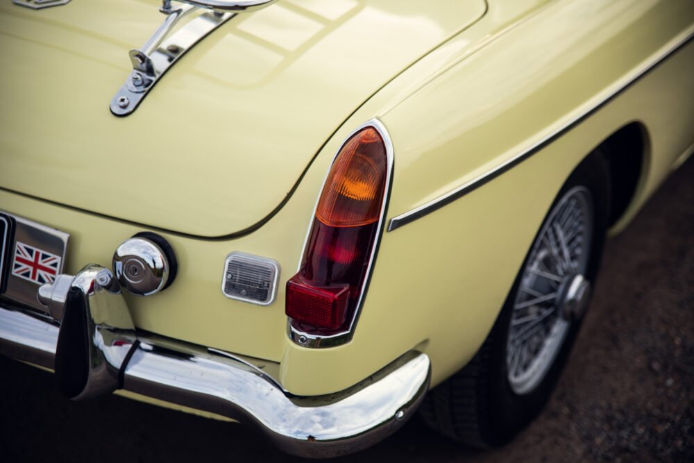 Vintage yellow car with UK flag and chrome details.