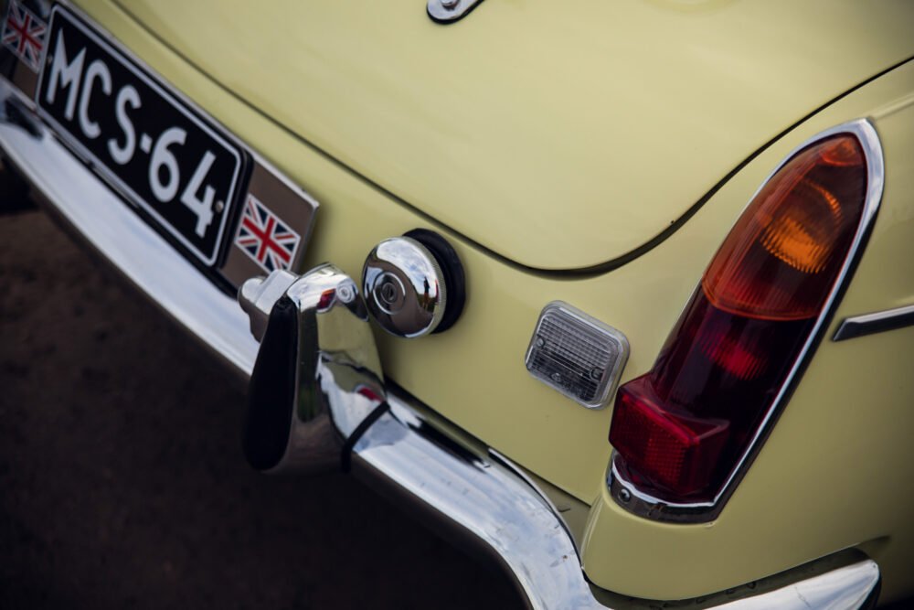 Vintage car's rear with British flag on license plate.