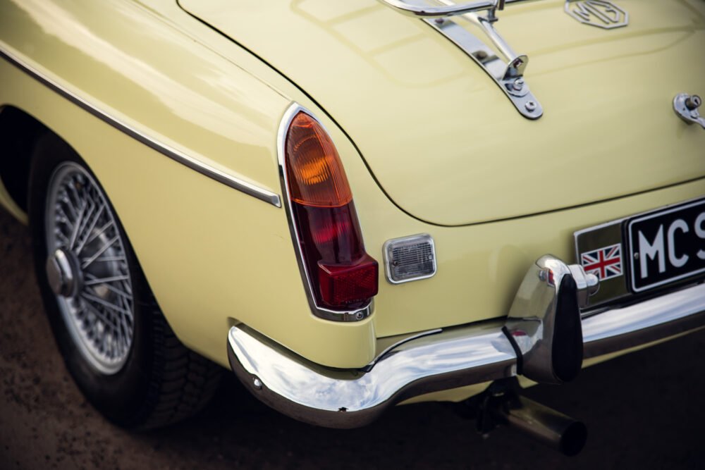 Vintage yellow car with British flag license plate.