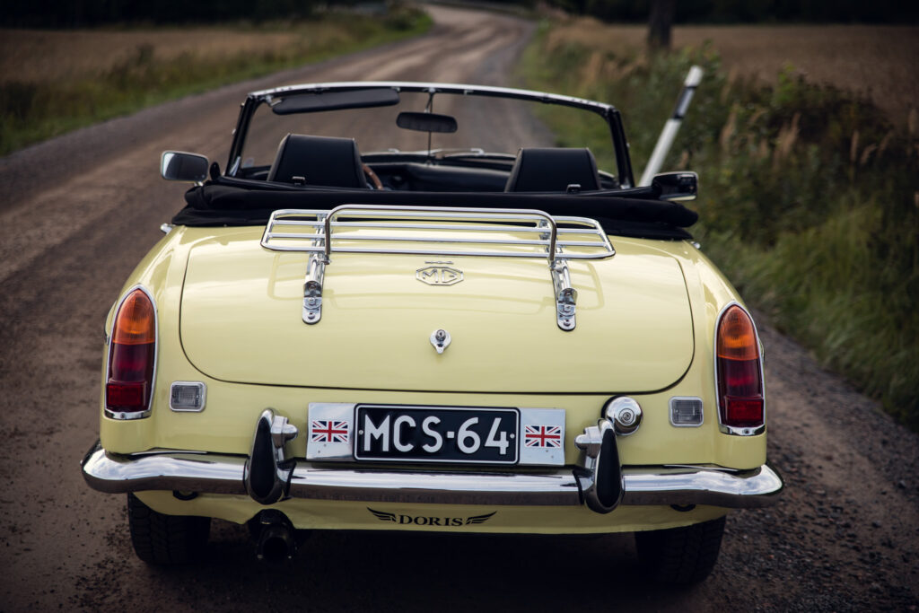 Yellow MG convertible car on country road.
