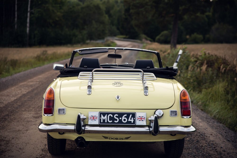 Yellow vintage convertible car on rural road.