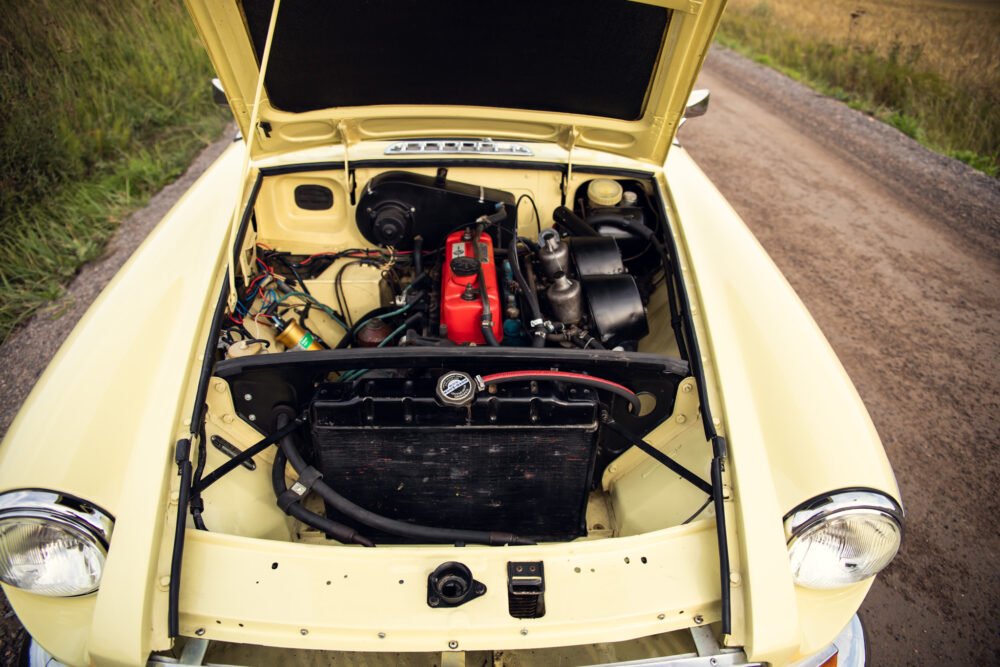 Vintage yellow car with open hood showing engine.