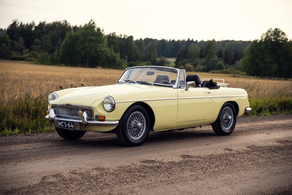 Yellow vintage convertible car on rural road.