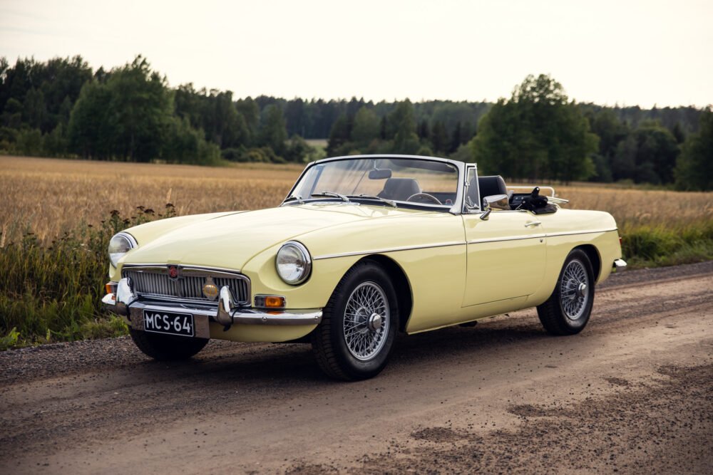 Vintage yellow convertible car on rural road.