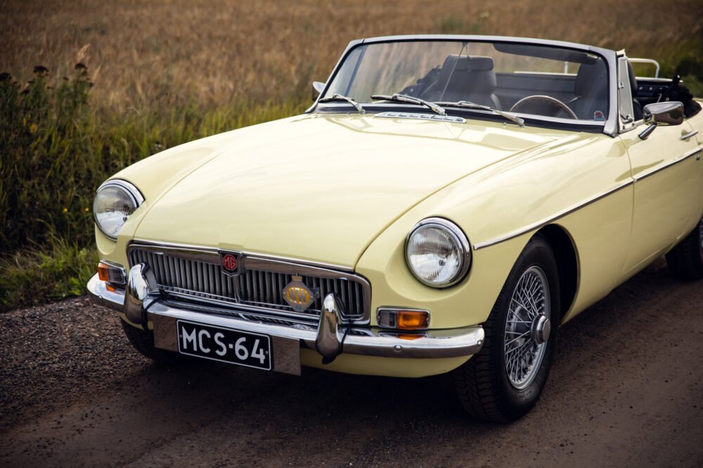 Vintage yellow MG convertible car on country road.