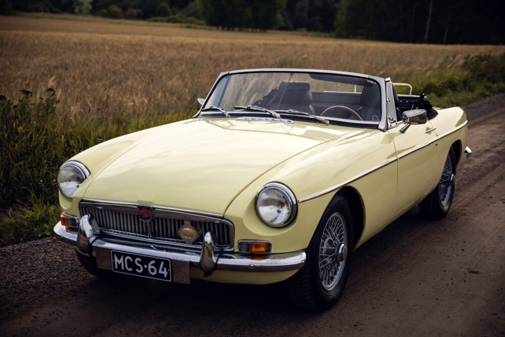 Yellow classic MG convertible on a rural road.