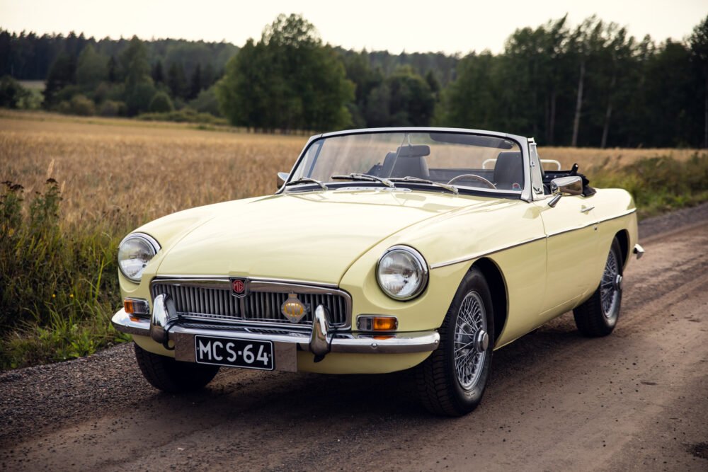 Vintage yellow MG convertible on rural road.