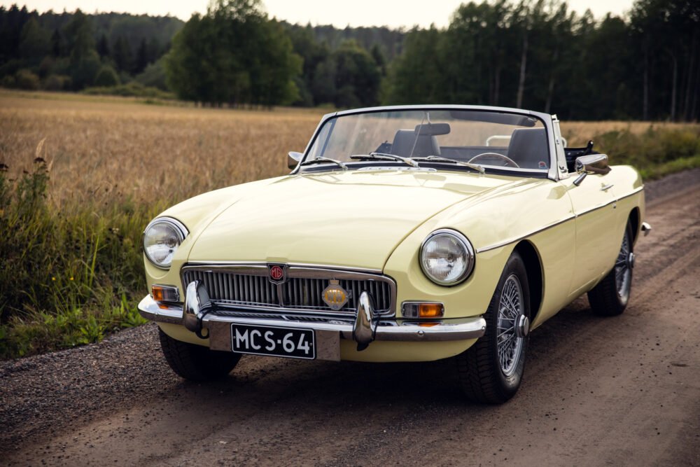 Yellow MG convertible car on rural road.