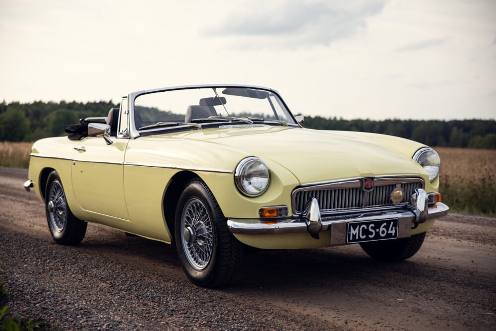 Vintage yellow MG convertible car on countryside road.