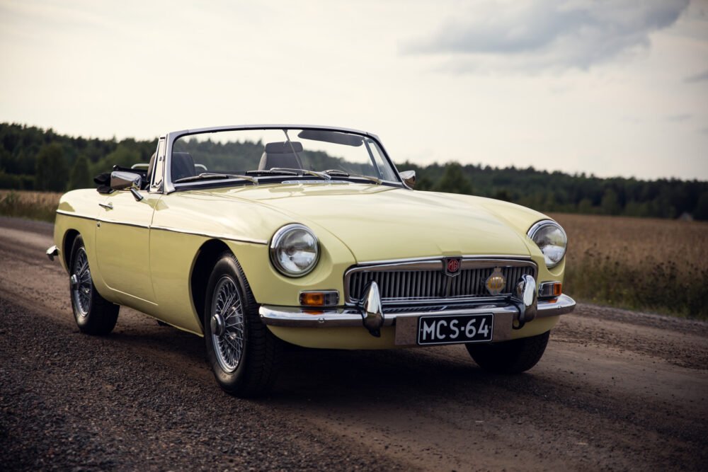 Vintage yellow MG convertible on rural road.