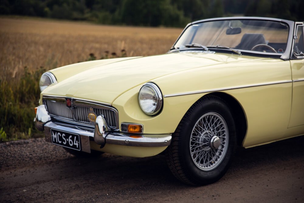 Vintage yellow MG car in rural setting.