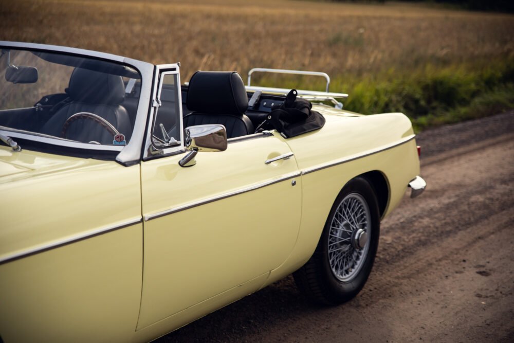 Vintage yellow convertible car on country road.