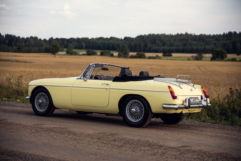 Vintage yellow convertible car on rural road.